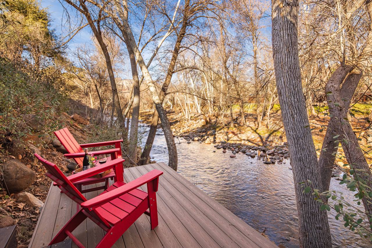 Red Adirondack chairs on private creek deck with wine and Oak Creek views