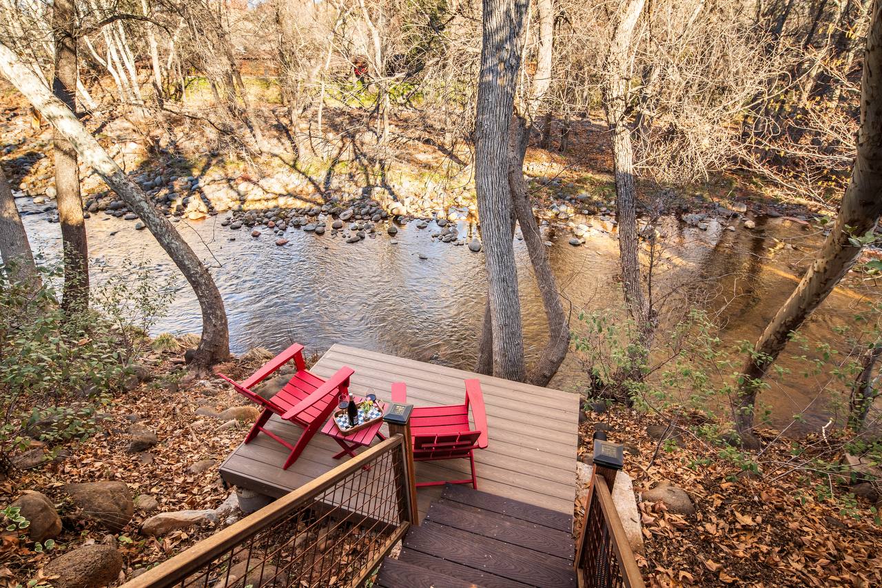 Private creek deck with red Adirondack chairs overlooking Oak Creek