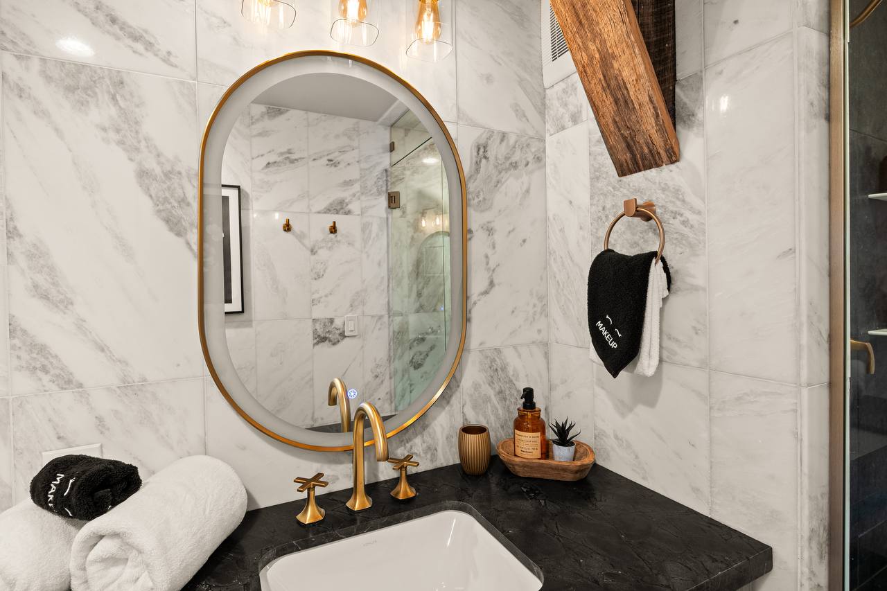Marble bathroom vanity with gold mirror and obsidian countertop