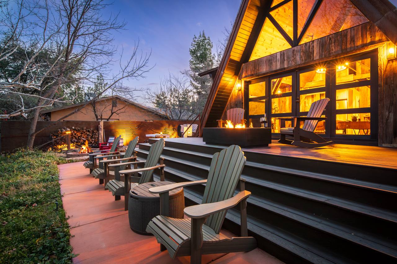 Green Adirondack chairs along deck with fire feature at dusk