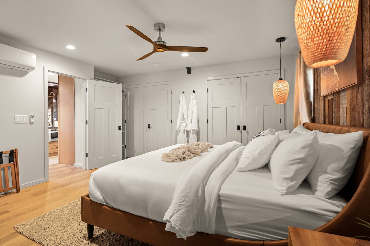 Primary bedroom with king bed, soft robes, and woven pendants